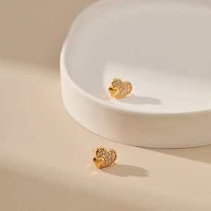 18K gold-plated double heart earrings with shimmering zircon stones on a white tray