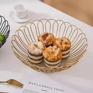 Elegant gold scallop-edged iron wire fruit basket for bread and snacks on a white table