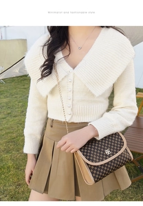 Detail of vintage patterned crossbody chain bag paired with a cream knit cardigan