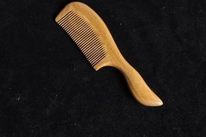 Detailed close-up showing the natural green sandalwood grain on a thick wooden comb handle