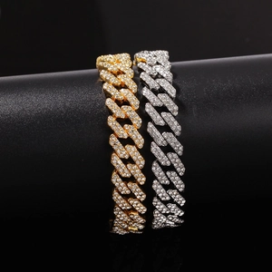 Close-up of gold and silver iced out Cuban link bracelets with sparkling crystals