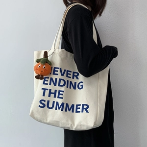 Minimalist canvas tote bag featuring blue summer text and orange fruit plush charm detail