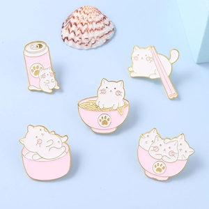 Vue détaillée de cinq épingles en émail de chats roses et blancs dans des bols