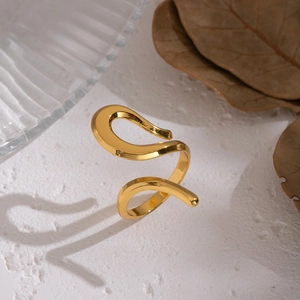 Minimalist gold geometric wavy open ring displayed on a textured white aesthetic background