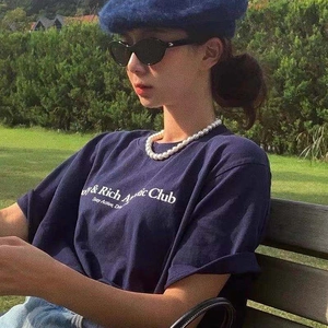 Detail of navy cotton t-shirt with white letter print worn with pearl necklace