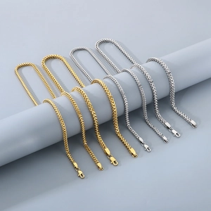 Detailed view of gold and silver wheat chains with secure lobster clasps on gray display
