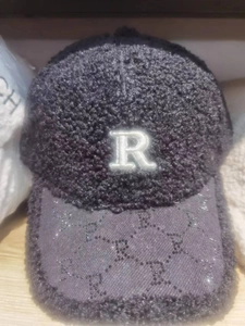 Detail of plush black baseball cap featuring an R embroidery and jacquard visor pattern