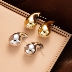 Close-up of polished gold and silver water drop earrings in a premium jewelry box