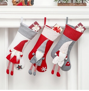 Three Nordic Christmas stockings with gnome dolls displayed on a fireplace mantel