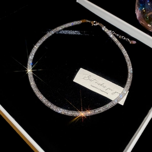 Macro shot of silver zircon choker on black velvet with glittering light effects