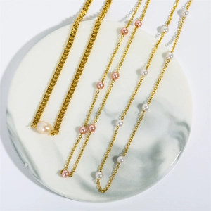 Three 18K gold plated stainless steel necklaces with white and pink pearls on marble tray