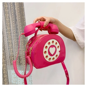 Detail of rose pink patent leather telephone bag with heart dial and Y2K aesthetic