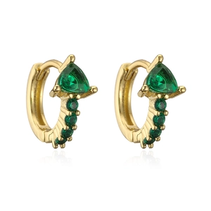 Dettaglio di orecchini a cerchio dorati con pietre di zircone verde e design geometrico