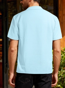 Vue arrière d'un polo bleu clair en maille gaufrée montrant la texture du tissu premium