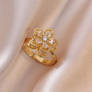 Macro shot of gold hollow flower ring with white zircons on soft champagne silk background