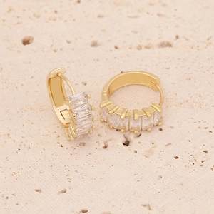 Detail of gold huggie earrings with micro-pave rectangular zircons on rock texture