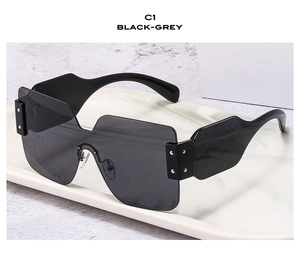 Detail of oversized black flat top sunglasses with dark grey lenses on marble tray