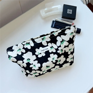 Close-up of black floral canvas makeup bag with a metal zipper and fabric label