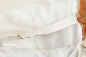 Detailed close-up of white silky lining and elastic waistband of printed halter dress