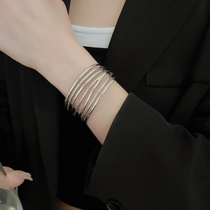 Detail of layered silver bangle set featuring smooth and twisted textures on wrist