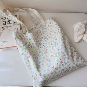 Close-up of floral cotton tote bag with woven label and soft pastel flower patterns