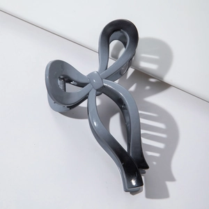 Detail shot of a matte gradient bow hair claw clip in grey and black on a white background