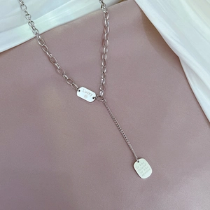 Macro detail of silver titanium Y-necklace with engraved lucky pendant and polished finish