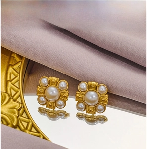 Détail de boucles d'oreilles vintage dorées avec perles blanches sur fond de soie