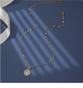 Detailed macro view of gold flower pendant with sparkling zircon on blue background