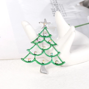 Christmas tree brooch with green enamel and colorful rhinestones on a display stand