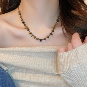 Gros plan d'un collier en perles d'œil de tigre irrégulières et perles métalliques sur un mannequin