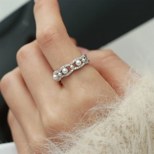 Detailed view of a wave-shaped silver ring featuring faux pearls and sparkling cubic zirconia