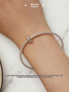 Detailed view of silver mesh textured open bangle bracelet with twisted center charm
