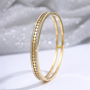 Macro shot of gold-plated bangle featuring double rows with crystal inlay and wave patterns