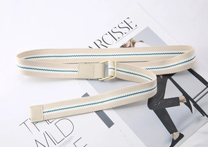 Close-up of beige canvas woven belt with green stripes and double D-ring metal buckle