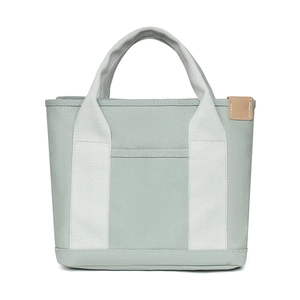 Detailed shot of mint green canvas tote bag showing stitching and brown leather patch