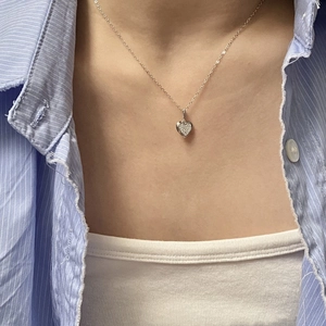Model wearing a S925 silver heart necklace with pavé cubic zirconia on a blue striped shirt