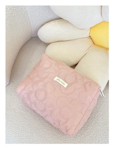 Gros plan détaillé d'une trousse de maquillage rose matelassée avec couture fleurie