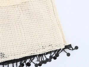 Makro-Detail von beige Strickkleid mit schwarzen Paillettenfransen und Perlenbesatz