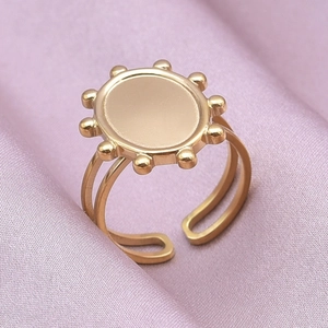 Macro shot of gold oval geometric ring with sunburst gear design on purple silk fabric