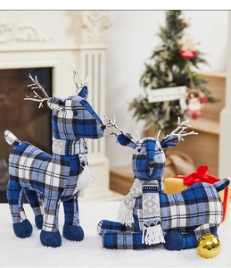 Close-up of blue plaid Christmas reindeer ornaments on a white faux fur rug