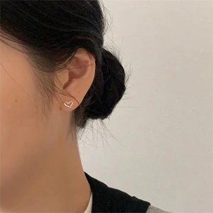 Close-up of minimalist silver heart stud earring worn on model's ear for daily style