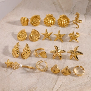 Flat lay of gold starfish rings and seashell earrings on stone background