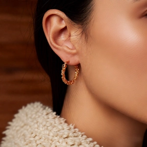 Close-up of 24k gold plated twisted rope hoop earrings worn by a model in casual style