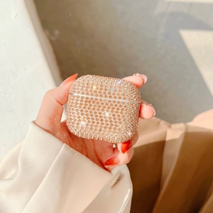 Close-up of luxury sparkling champagne gold rhinestones on AirPods case held in hand