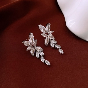 Macro shot of silver bow tassel earrings with marquise-cut marquise stones on red fabric