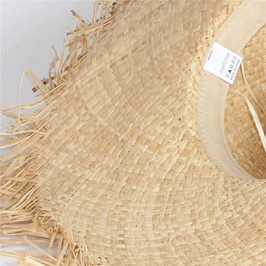 Detail shot of 100% Raffia straw hat label and woven texture with frayed edge detail