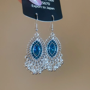 Dettaglio di orecchini vintage bohémien in argento con cristallo blu e nappe in metallo