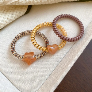 Close-up of spiral hair ties with checkered heart and star pendants on fabric