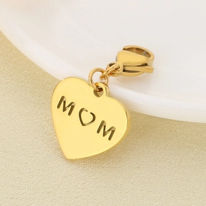 Detail of a golden heart-shaped MOM pendant with hollow design on beige textured fabric